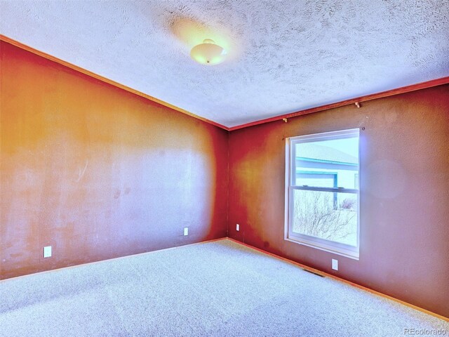 unfurnished room featuring visible vents, a textured ceiling, carpet, and baseboards