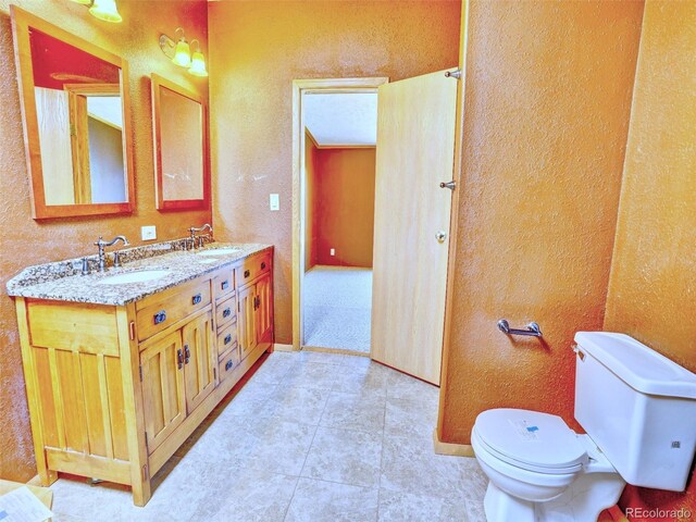 bathroom with a sink, a textured wall, and toilet