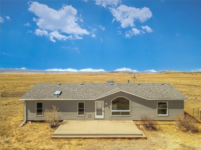 back of house featuring a shingled roof and a deck with mountain view