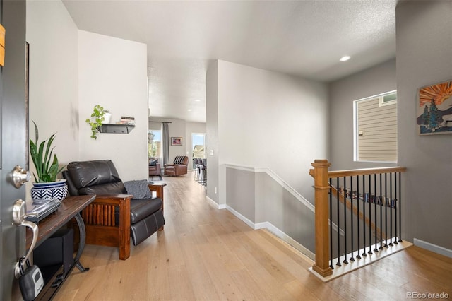 hallway featuring an upstairs landing, wood finished floors, baseboards, and recessed lighting