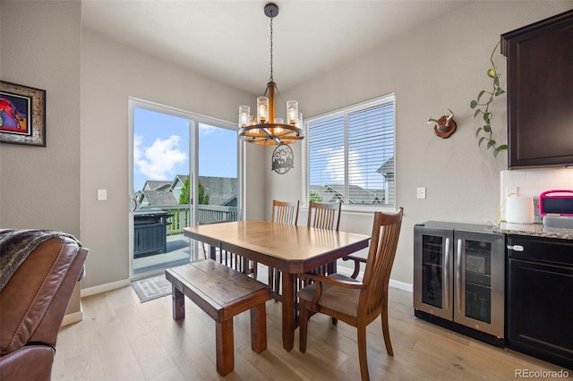 dining area with wine cooler, a chandelier, light wood-style flooring, and baseboards