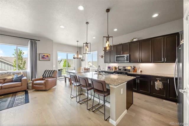 kitchen with stainless steel appliances, a sink, light wood-style flooring, open floor plan, and recessed lighting
