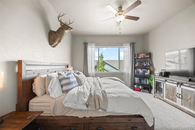 carpeted bedroom with ceiling fan and a textured wall