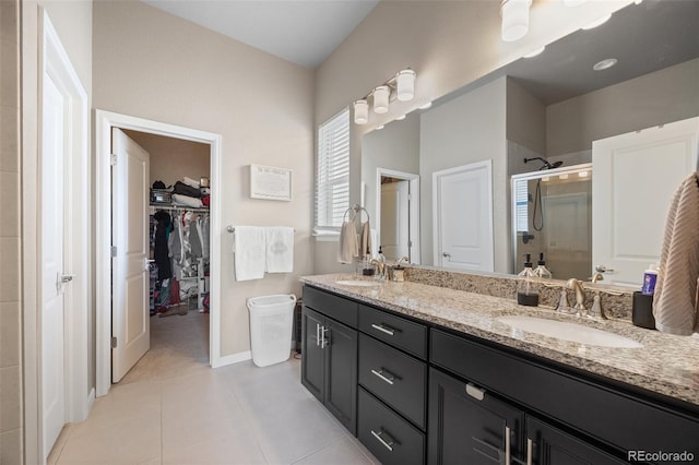 bathroom with a stall shower, a spacious closet, double vanity, tile patterned floors, and baseboards