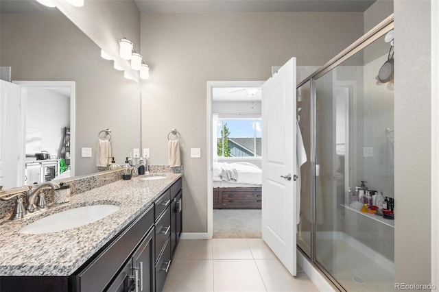 ensuite bathroom featuring a stall shower, tile patterned floors, double vanity, and baseboards