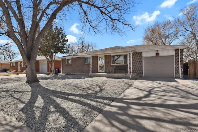 single story home featuring a garage, brick siding, driveway, and fence