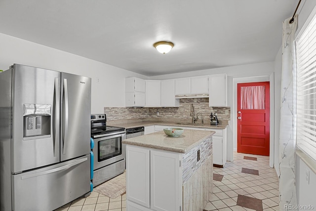 kitchen featuring light tile patterned floors, decorative backsplash, appliances with stainless steel finishes, white cabinets, and a sink