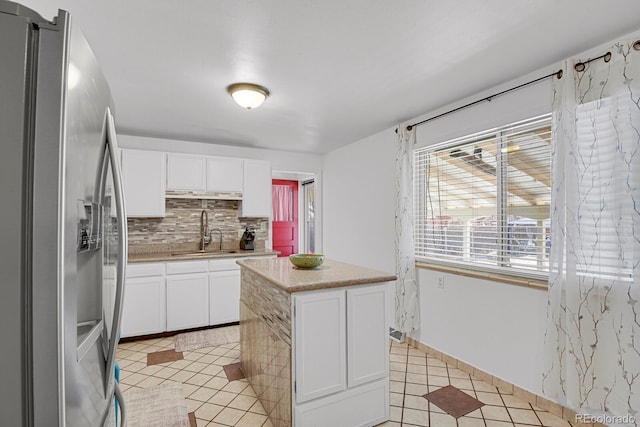 kitchen with tasteful backsplash, white cabinets, stainless steel fridge with ice dispenser, light countertops, and a sink