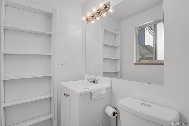 bathroom with a chandelier, vanity, and toilet