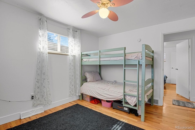 bedroom with baseboards, visible vents, and wood finished floors