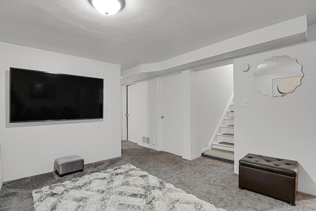 below grade area featuring stairs, carpet floors, a textured ceiling, and visible vents