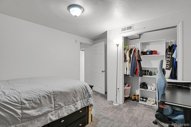 bedroom with a textured ceiling, carpet floors, a closet, and visible vents