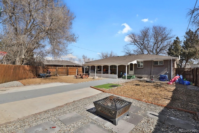 rear view of property with a patio area, brick siding, a fire pit, and a fenced backyard