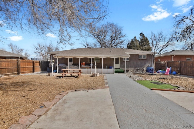 ranch-style house featuring driveway, a fenced backyard, and brick siding