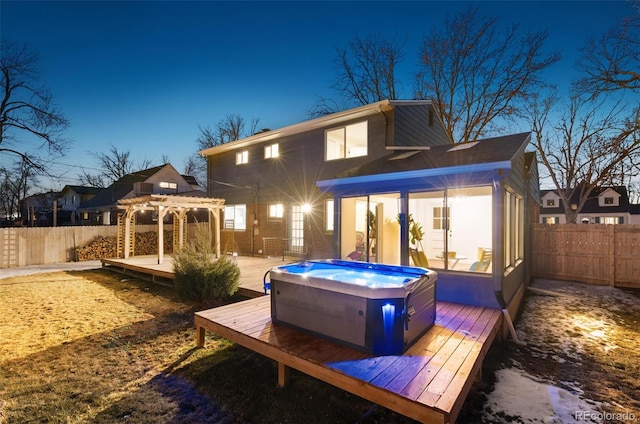 back of house featuring a pergola, a wooden deck, and a hot tub