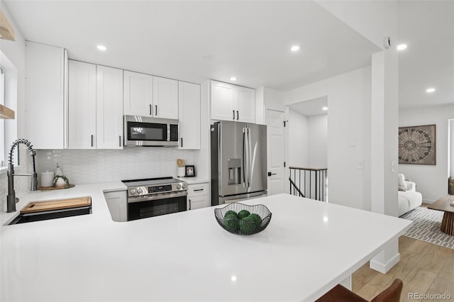 19954 E Dartmouth Ave, Aurora, CO 80013 - kitchen with appliances with stainless steel finishes, light wood-type flooring, backsplash, light countertops, and a peninsula