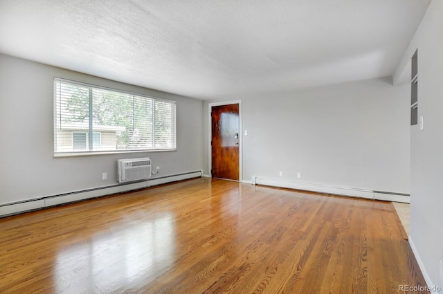 10491 W 7th Pl, Lakewood, CO 80215 - unfurnished room featuring baseboard heating, wood finished floors, an AC wall unit, and baseboards