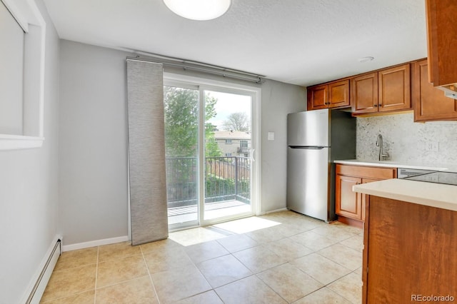 10491 W 7th Pl, Lakewood, CO 80215 - kitchen with freestanding refrigerator, a baseboard heating unit, light countertops, brown cabinetry, and a sink