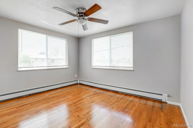 10491 W 7th Pl, Lakewood, CO 80215 - empty room with healthy amount of natural light, a baseboard heating unit, wood finished floors, and a ceiling fan