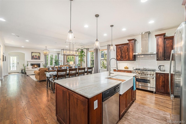 3357 N Akron Ct, Denver, CO 80238 - kitchen featuring wall chimney range hood, appliances with stainless steel finishes, light wood-style floors, recessed lighting, and tasteful backsplash