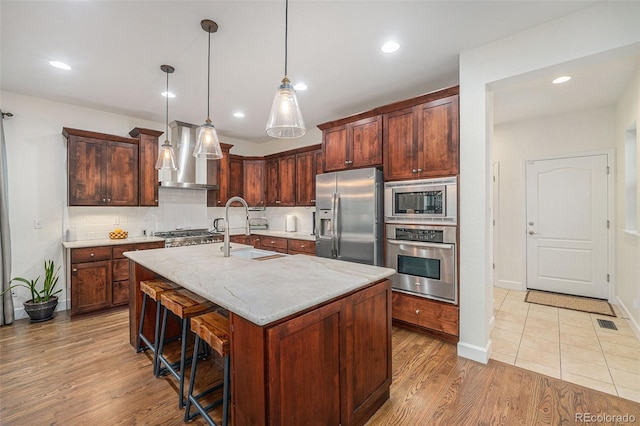 3357 N Akron Ct, Denver, CO 80238 - kitchen with stainless steel appliances, tasteful backsplash, light wood finished floors, decorative light fixtures, and a center island with sink