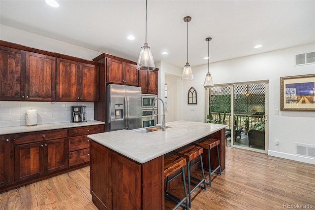 3357 N Akron Ct, Denver, CO 80238 - kitchen with stainless steel appliances, light wood-type flooring, light countertops, tasteful backsplash, and a breakfast bar