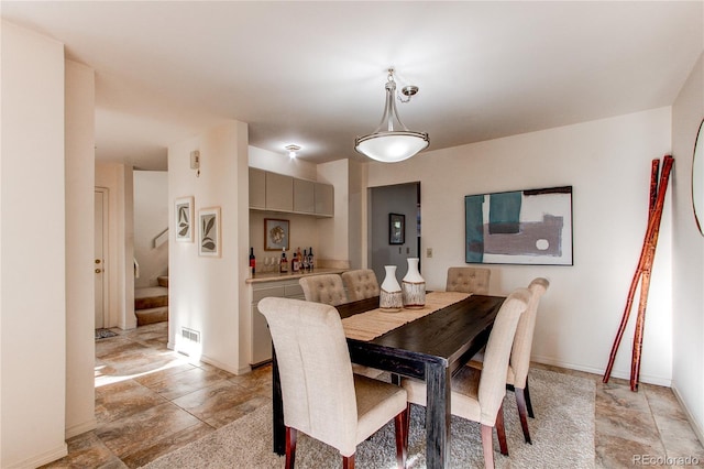 1530 S Quebec Way Unit 29, Denver, CO 80231 - dining room featuring stone tile flooring, baseboards, visible vents, indoor bar, and stairway