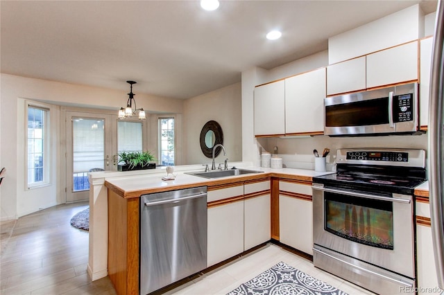 1530 S Quebec Way Unit 29, Denver, CO 80231 - kitchen with a sink, a peninsula, stainless steel appliances, white cabinetry, and light countertops