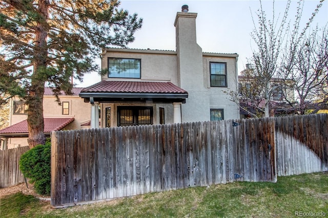 1530 S Quebec Way Unit 29, Denver, CO 80231 - view of front facade featuring a chimney, stucco siding, a tile roof, and fence private yard