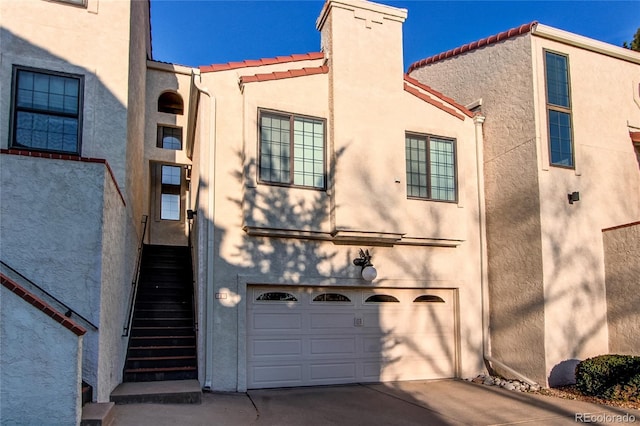 1530 S Quebec Way Unit 29, Denver, CO 80231 - exterior space featuring a tile roof, concrete driveway, a garage, stucco siding, and a chimney