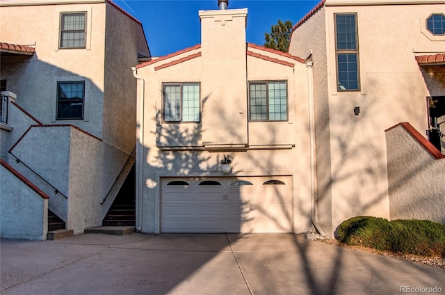 1530 S Quebec Way Unit 29, Denver, CO 80231 - exterior space with concrete driveway, a garage, stucco siding, stairway, and a chimney