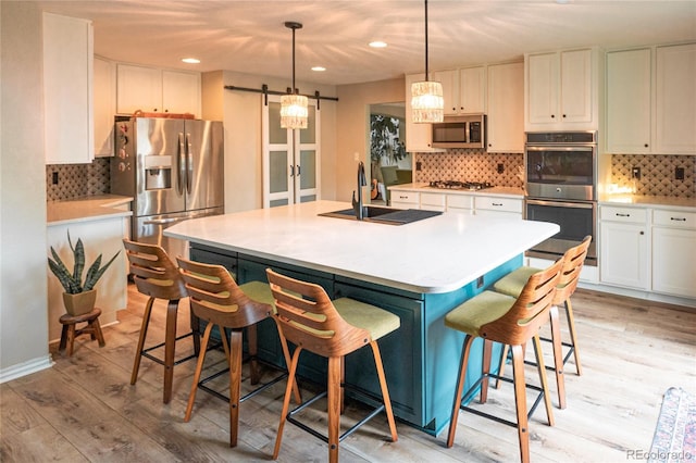 919 Taylor Ln, Erie, CO 80516 - kitchen with appliances with stainless steel finishes, a barn door, light wood-style floors, backsplash, and recessed lighting
