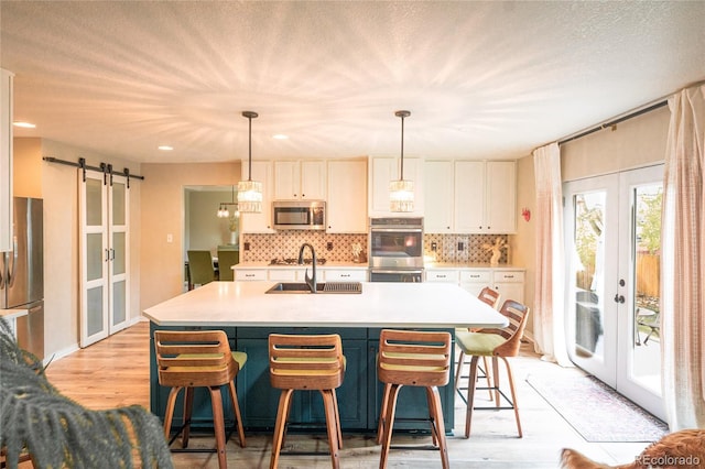 919 Taylor Ln, Erie, CO 80516 - kitchen featuring stainless steel appliances, french doors, a barn door, white cabinets, and tasteful backsplash