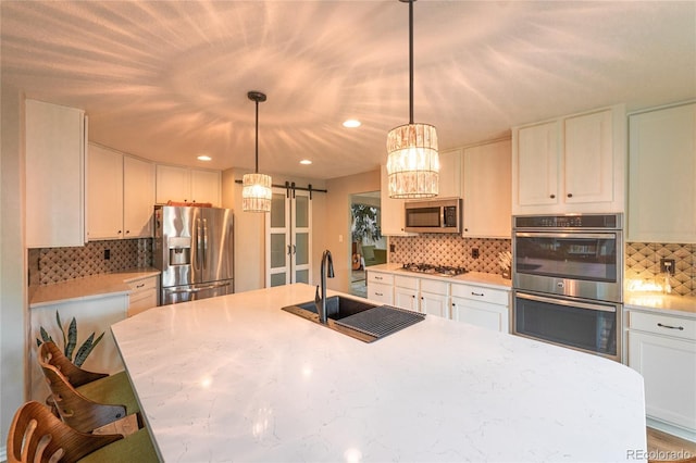919 Taylor Ln, Erie, CO 80516 - kitchen featuring appliances with stainless steel finishes, a barn door, backsplash, white cabinets, and recessed lighting