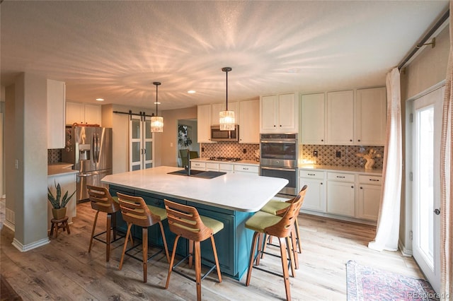 919 Taylor Ln, Erie, CO 80516 - kitchen with stainless steel appliances, a barn door, light wood-type flooring, white cabinets, and recessed lighting