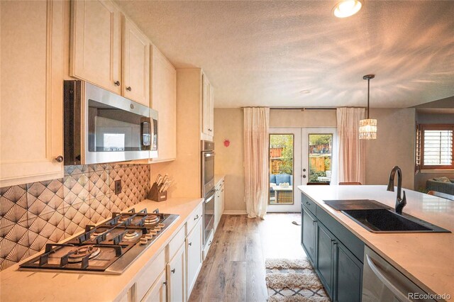 919 Taylor Ln, Erie, CO 80516 - kitchen with stainless steel appliances, light countertops, light wood-style flooring, tasteful backsplash, and french doors