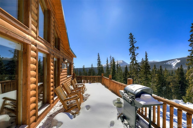 snow covered patio featuring a mountain view and a grill