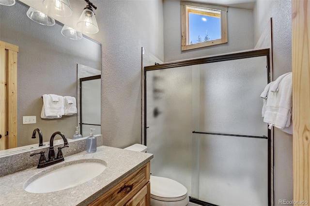 bathroom featuring vanity, a shower with shower door, and toilet