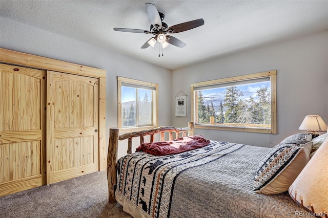 bedroom with ceiling fan, carpet, and a textured ceiling