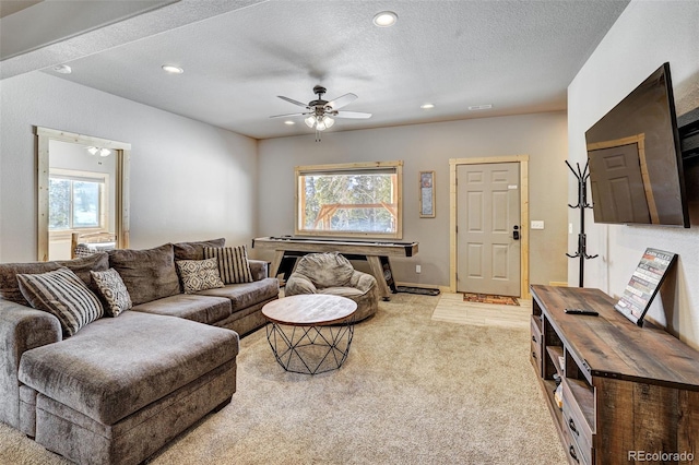 carpeted living room with ceiling fan, plenty of natural light, and a textured ceiling