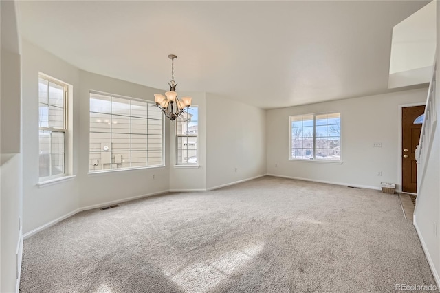 carpeted empty room with a notable chandelier