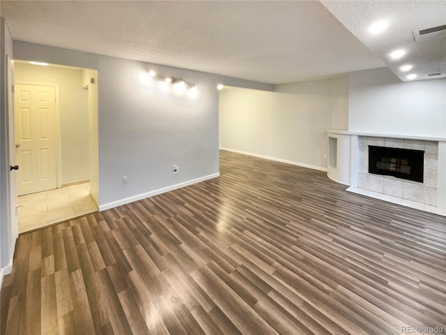 unfurnished living room with a tile fireplace, a textured ceiling, and dark hardwood / wood-style floors