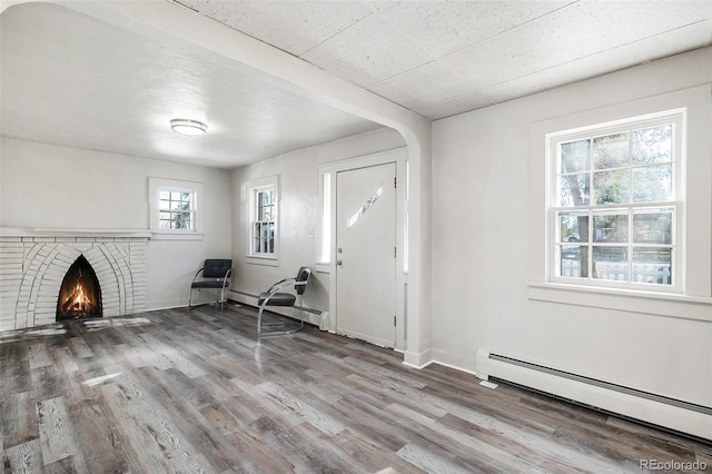 entrance foyer featuring hardwood / wood-style flooring, a brick fireplace, and baseboard heating