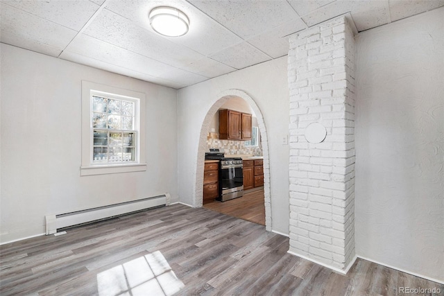 unfurnished living room with a paneled ceiling, light hardwood / wood-style flooring, and a baseboard radiator