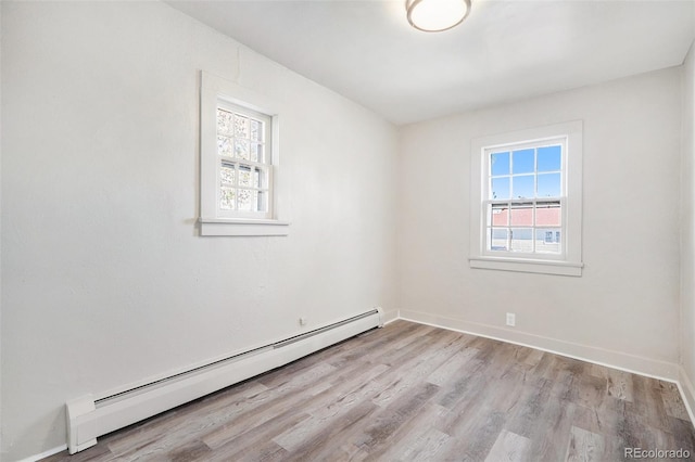 empty room with a wealth of natural light, light hardwood / wood-style flooring, and a baseboard radiator