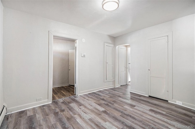 unfurnished bedroom featuring wood-type flooring and a baseboard radiator