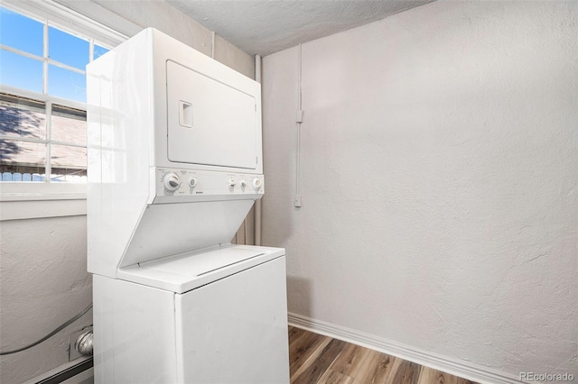 washroom featuring a textured ceiling, hardwood / wood-style flooring, and stacked washer / dryer