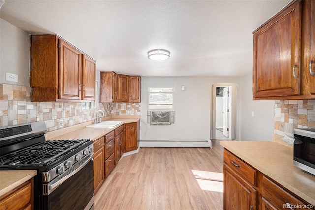 kitchen featuring sink, a baseboard radiator, stainless steel gas range, light hardwood / wood-style flooring, and backsplash