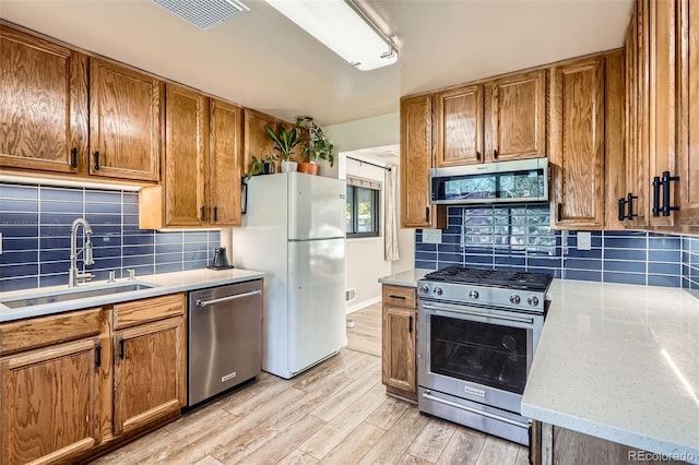 3224 Troy St, Aurora, CO 80011 - kitchen featuring appliances with stainless steel finishes, a sink, light wood-style flooring, light countertops, and decorative backsplash