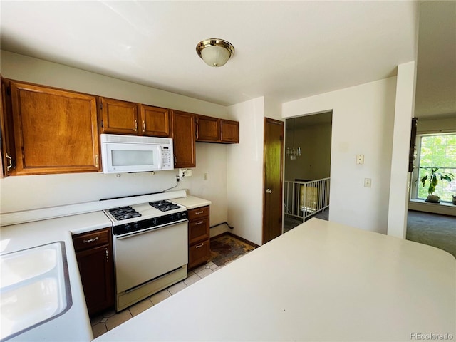 kitchen featuring white appliances, a sink, light countertops, and light tile patterned floors
